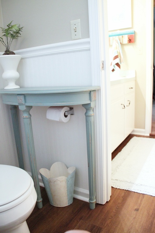 Add a half table over a toilet paper holder for extra storage