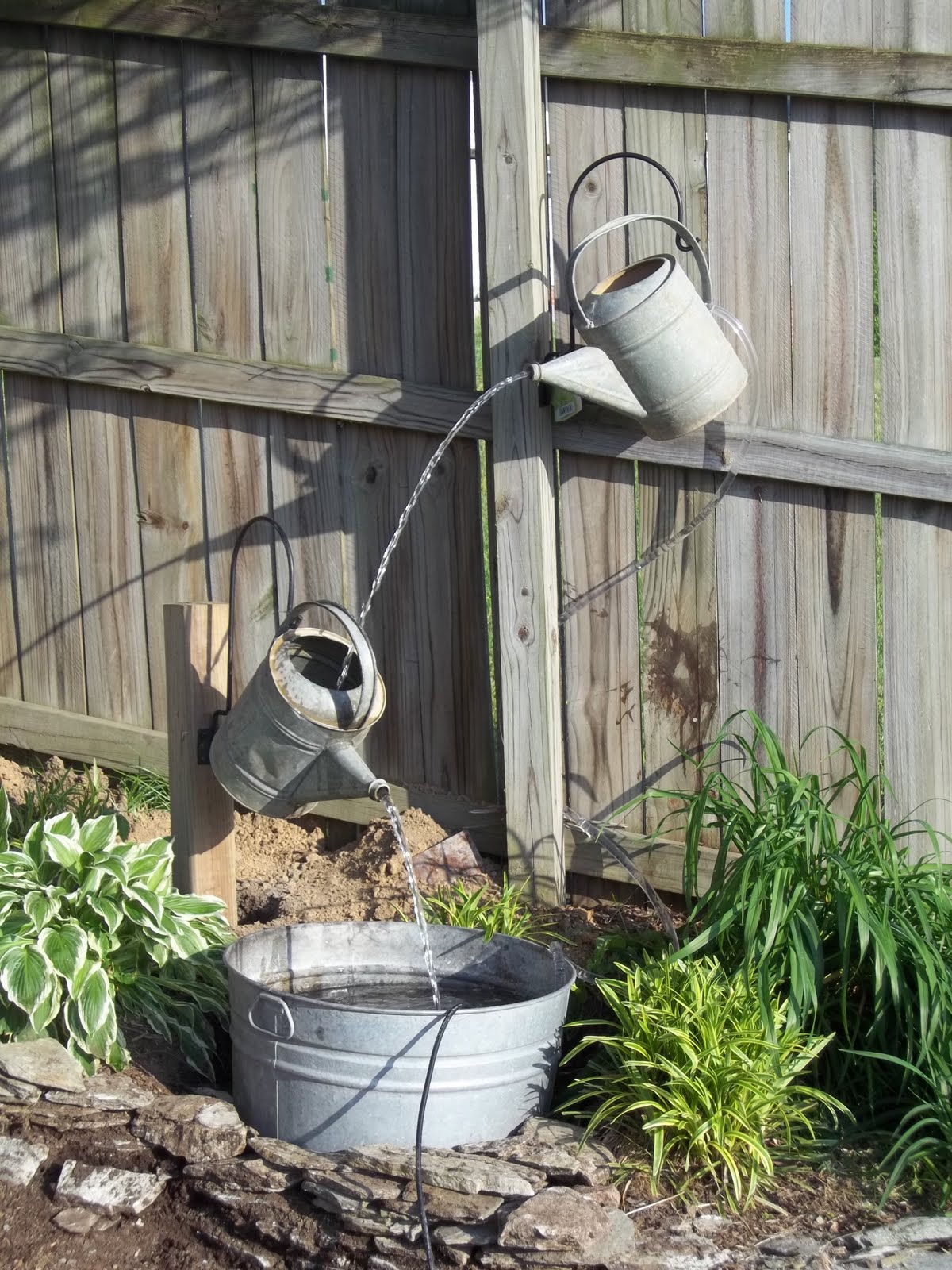 Create a small water feature using your old watering cans and pails
